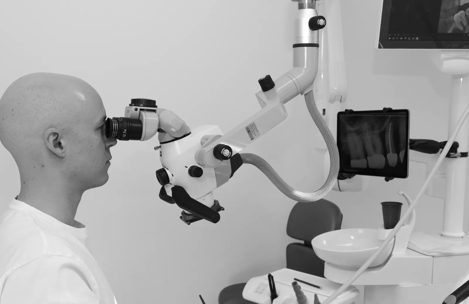 Dr. Philipp Brenner, Endodontologe in Stuttgart, arbeitet konzentriert unter dem Dentalmikroskop während einer endodontischen Behandlung